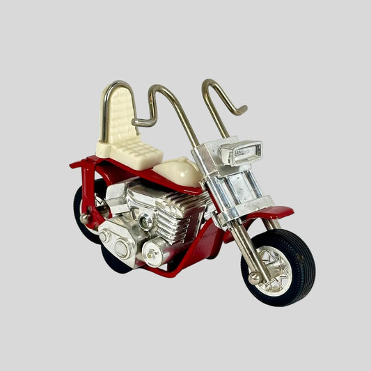 Model motorcycle with red body, silver engine, and white seat on a light gray background