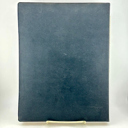 Black faux leather bound book against white background. 