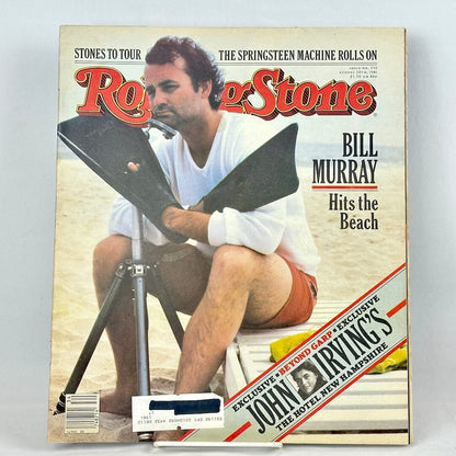 A vintage issue of Rolling Stone magazine featuring Bill Murray on the cover, seated on a beach chair on a sandy beach. 