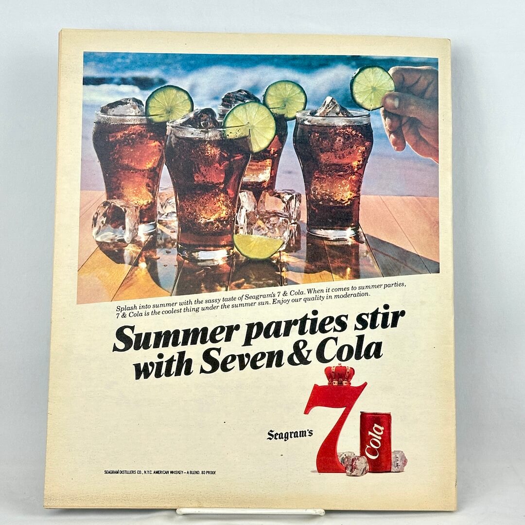 Back cover featuring vintage Seagram's 7-Cola summer advertisement with image of line of drinks on table in front of ocean. 