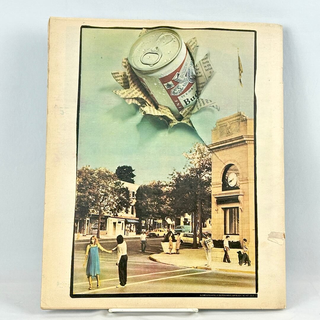 Back cover of magazine with beer ad against light surface. 