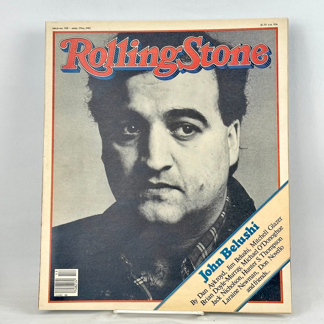 A vintage Rolling Stone magazine cover featuring a black-and-white portrait of John Belushi.