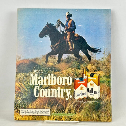 Back cover of magazine with full page Marlboro ad featuring mounted cowboy riding through field. 