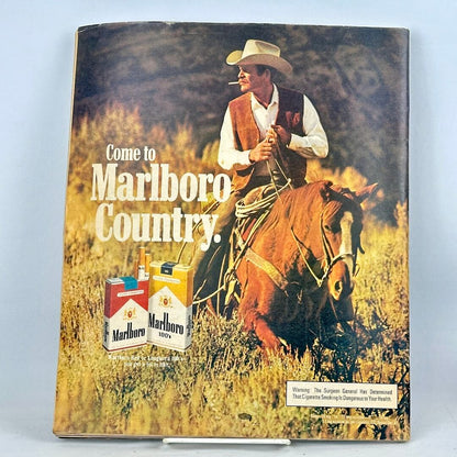 Back cover of magazine with full page Marlboro cigarette ad with image of smoking, mounted cowboy. 