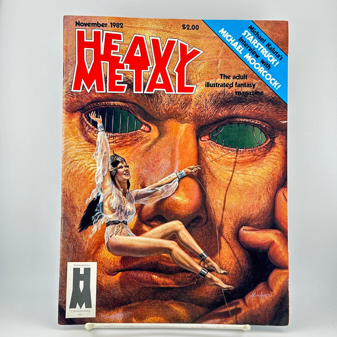 Heavy Metal magazine cover featuring the iconic red and white logo and cover art of a giant face with a woman floating in front of it. 