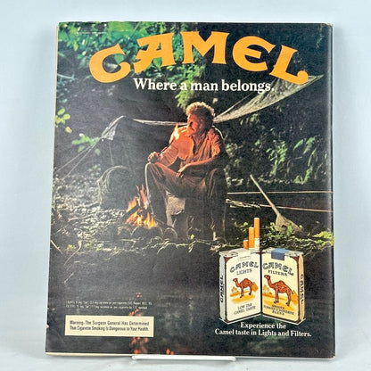 Vintage Camel cigarette advertisement on magazine back cover showing a man sitting by a campfire in a forest.