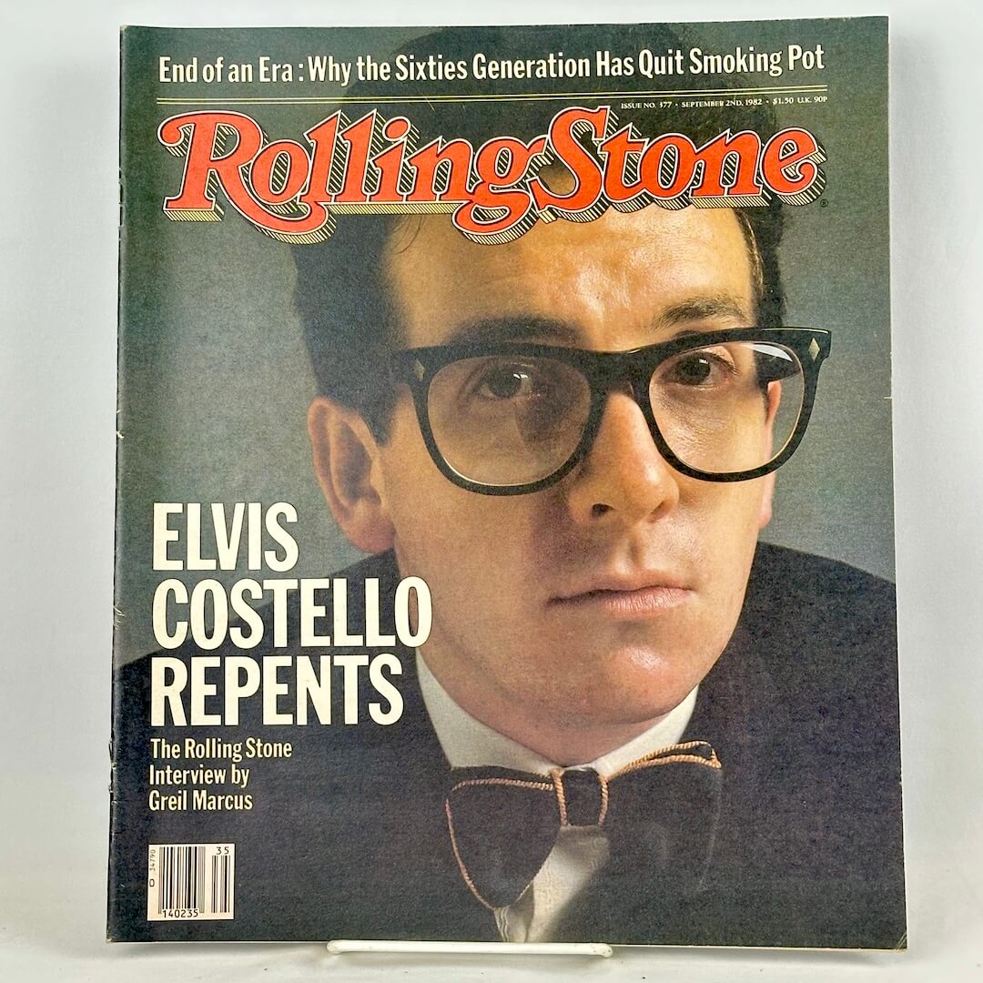 A vintage Rolling Stone magazine cover featuring a close-up portrait of Elvis Costello wearing black-rimmed glasses.