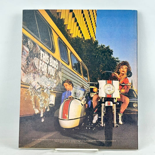 Back cover of magazine showing an ad with woman riding a white motorcycle with a sidecar next to a yellow bus.