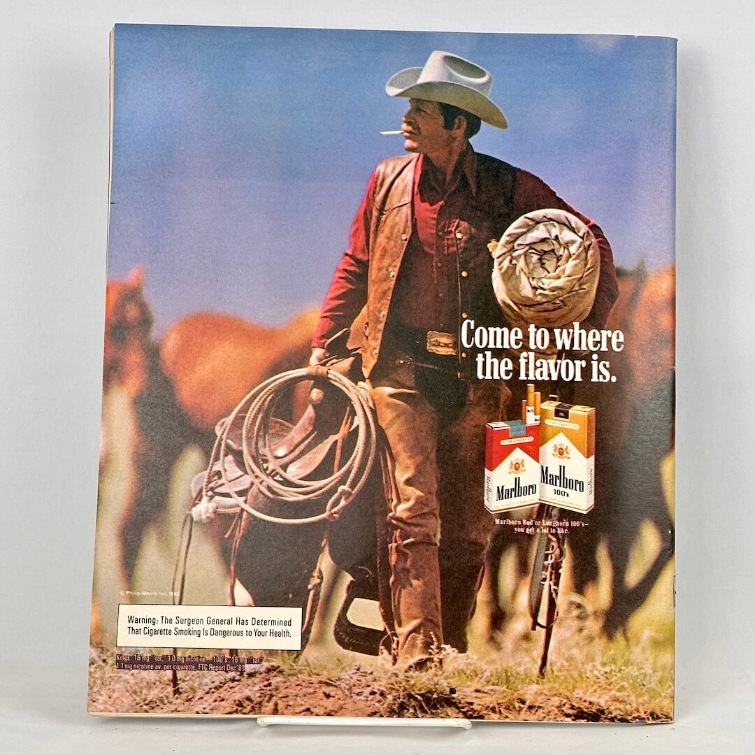 Back cover of magazine with full page ad for Marlboro cigarettes featuring a cowboy carrying a saddle. 