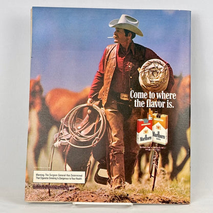 Back cover of magazine with full page ad for Marlboro cigarettes featuring a cowboy carrying a saddle. 