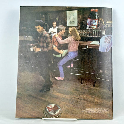 Back cover of magazine with full page ad for Budweiser with picture of people at a bar. 