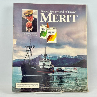 Back cover of magazine with full page ad for Merit cigarettes featuring image of boat and plan on mountain lake. 