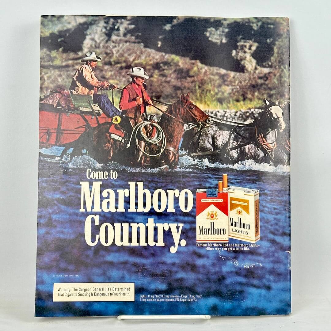 Back cover of magazine with full page ad for Marlboro cigarettes featuring mounted cowboys wading through water. 