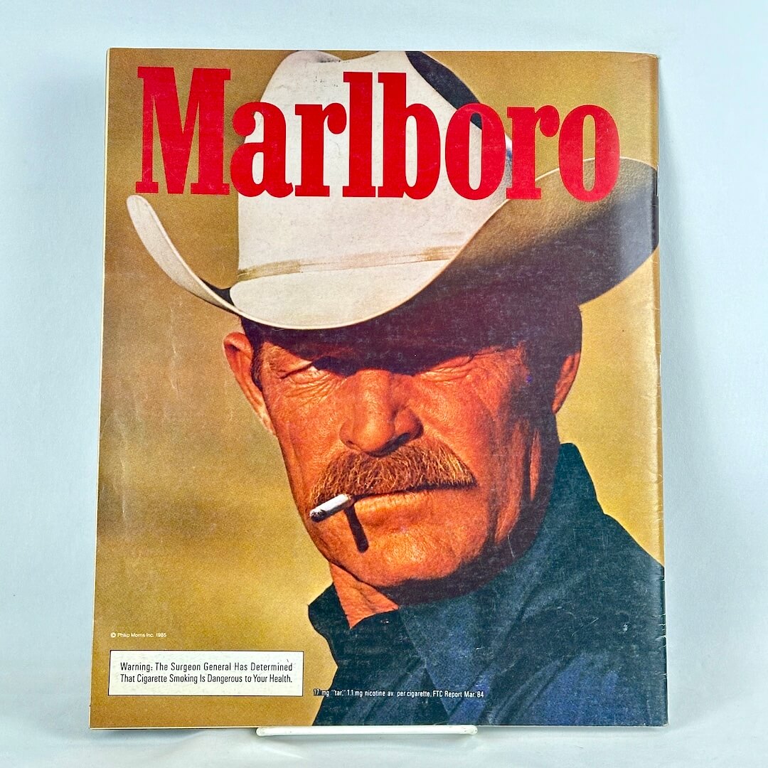 Back cover of magazine with full page ad for Marlboro cigarettes featuring up close portrait of smoking cowboy.