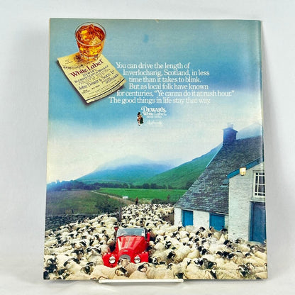 Back cover of magazine with full page ad for Dewar's White Label with image of red car among herd of sheep.