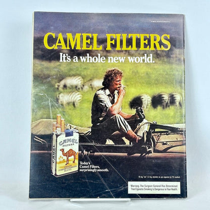 Back cover of magazine with full page ad for Camel cigarettes featuring image of man sitting in car smoking among zebras.