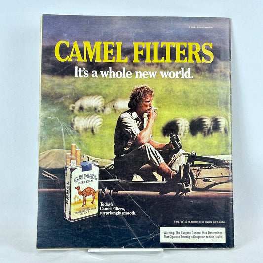 Back cover of magazine with full page ad for Camel cigarettes featuring image of man sitting in car smoking among zebras.