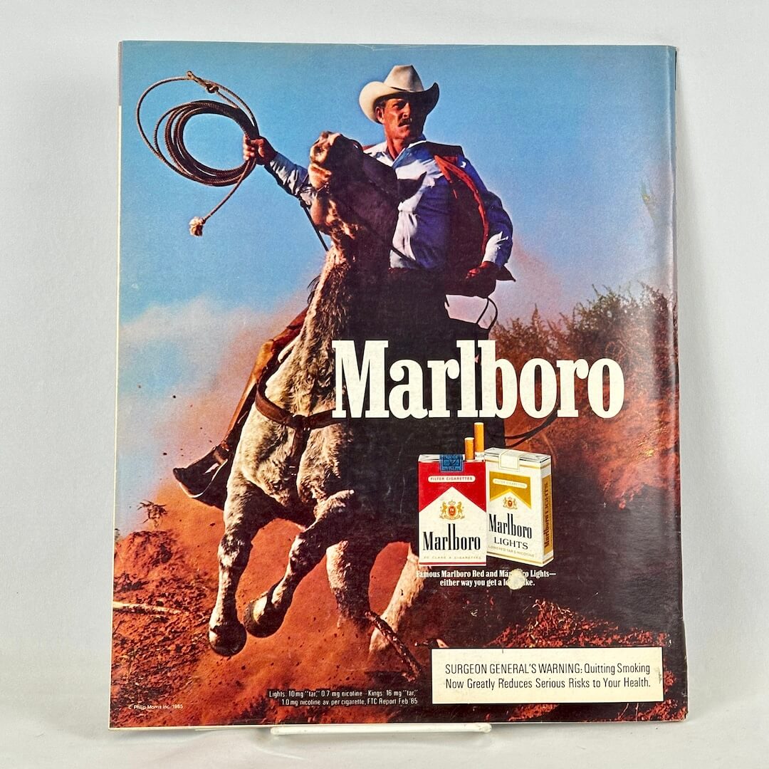 Back cover of magazine with full page ad for Marlboro cigarettes featuring horse-riding cowboy and cigarette packs.