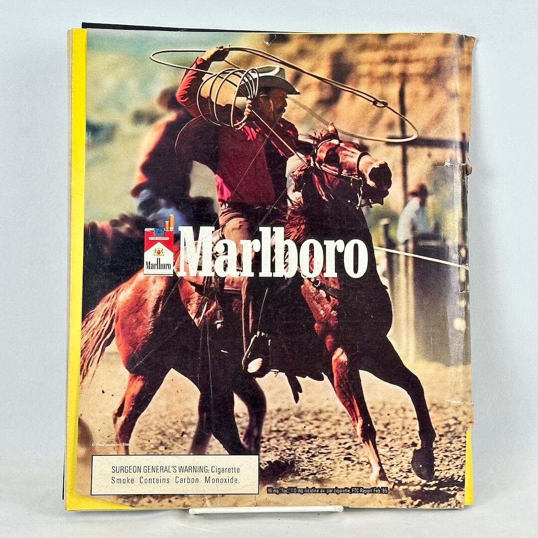 Back cover of magazine with full page ad for Marlboro cigarettes featuring roping cowboy on horseback. 