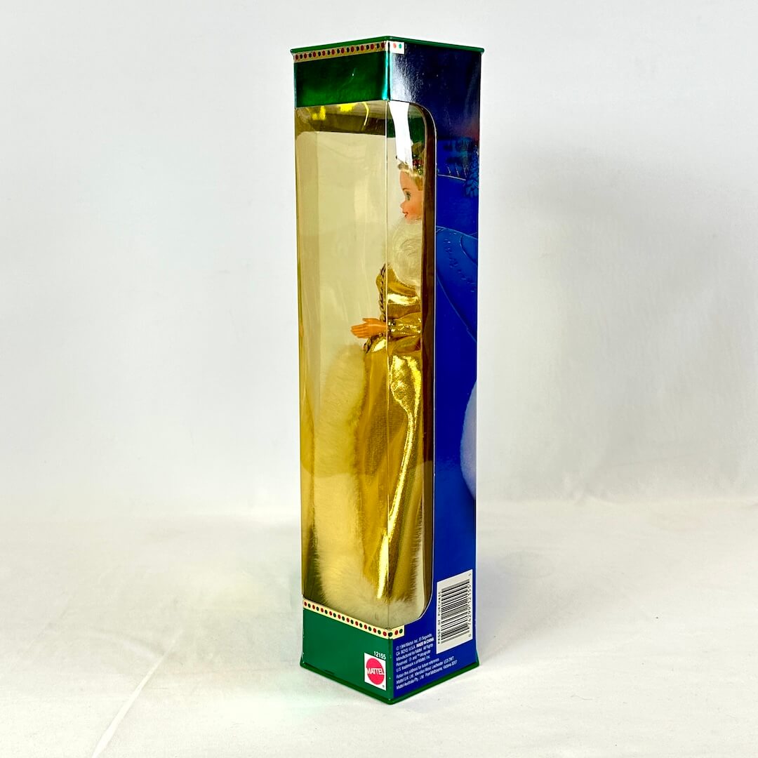 Barbie in gold dress still sealed in box, side view.