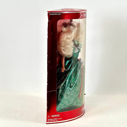 Barbie doll in a green dress inside a cylindrical packaging with a red top on a white background