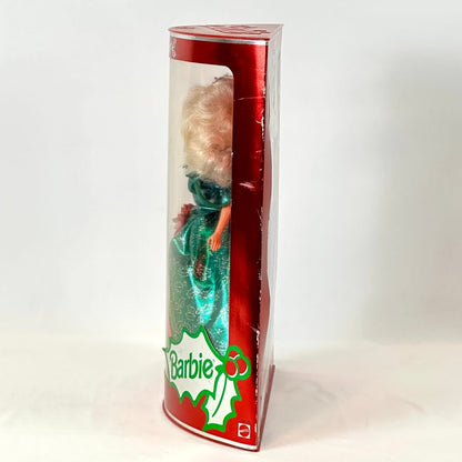 Barbie doll in a green dress inside a red and white box with 'Barbie' branding.