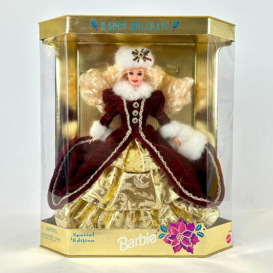 Barbie doll in a festive outfit with gold packaging, featuring the 'Happy Holidays' text.