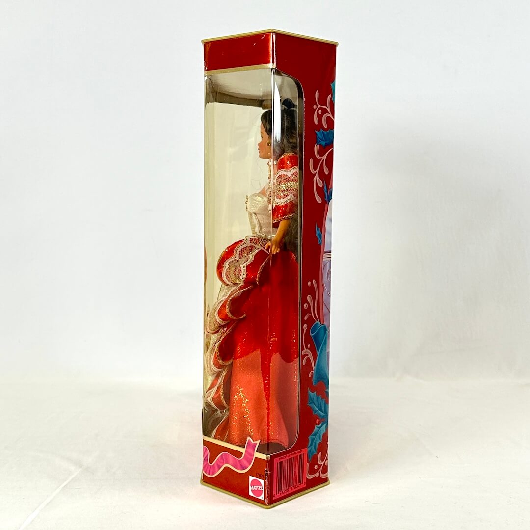 Doll in a decorative box with red and gold design on a white background