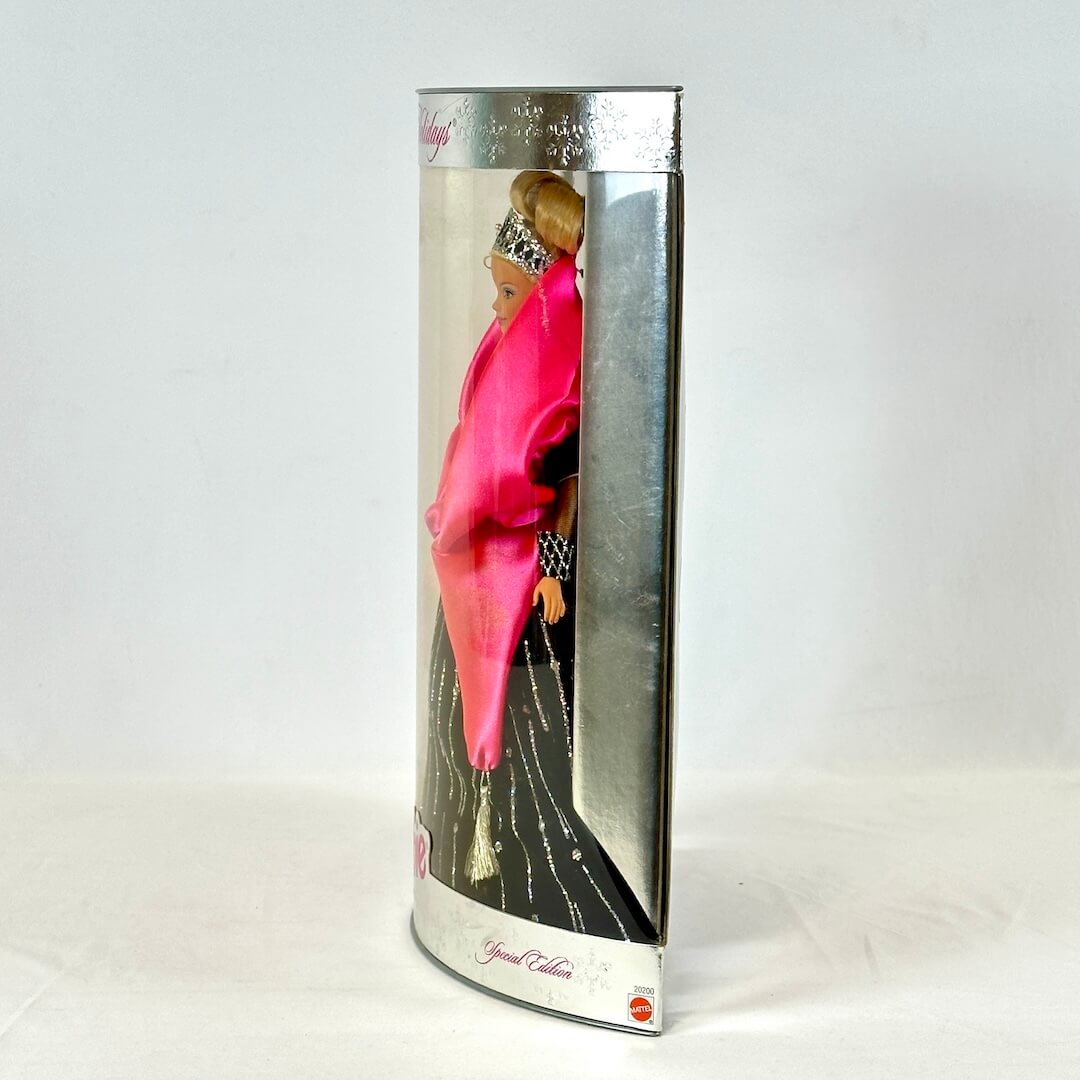 Barbie doll in a black dress with a silver tiara in packaging on a white background