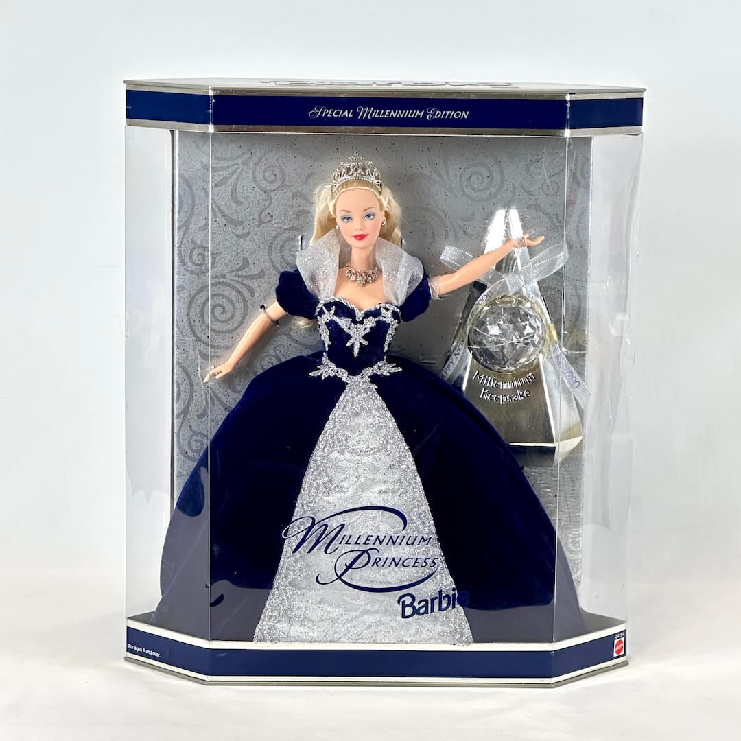 Barbie doll in a navy blue and white gown with a tiara, displayed in a clear box.