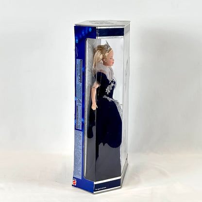 Doll in a blue dress with a tiara inside a clear box on a white background