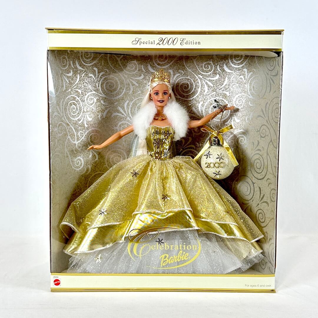 Barbie doll in a gold dress with a white fur boa in a decorative box.