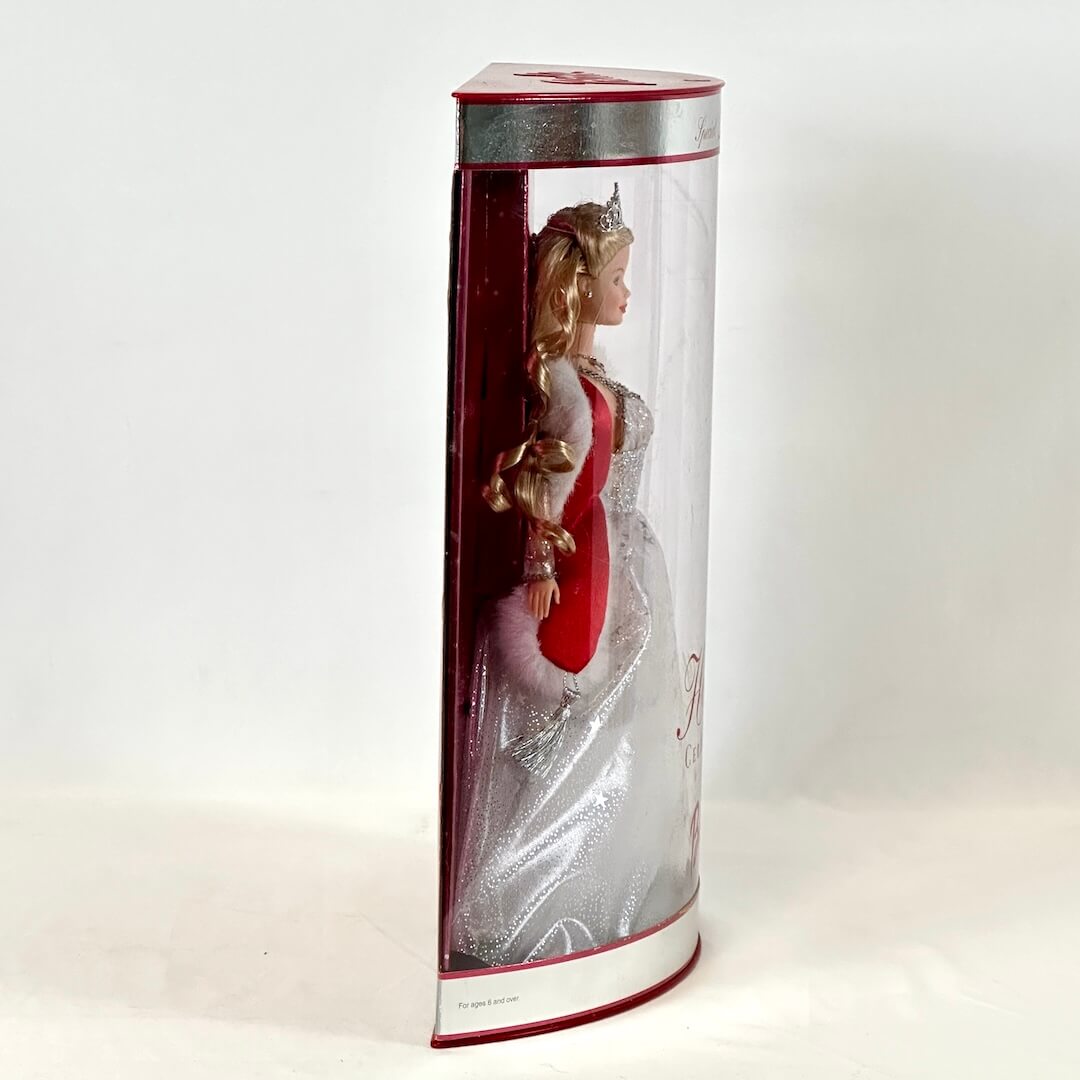 Barbie doll in a red and white dress inside a cylindrical packaging on a white background