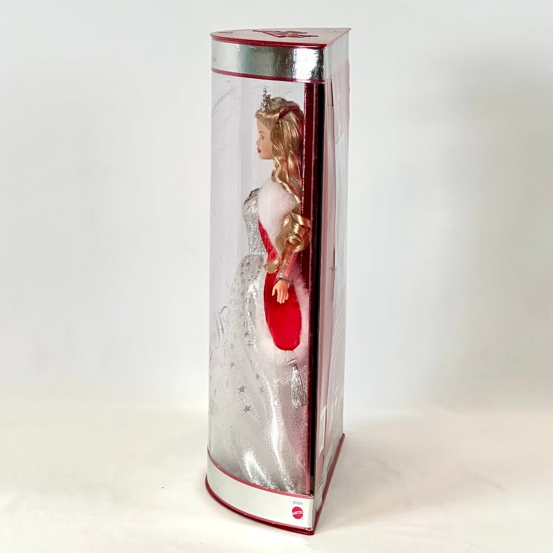 Doll in a transparent box with a red and white dress on a white background