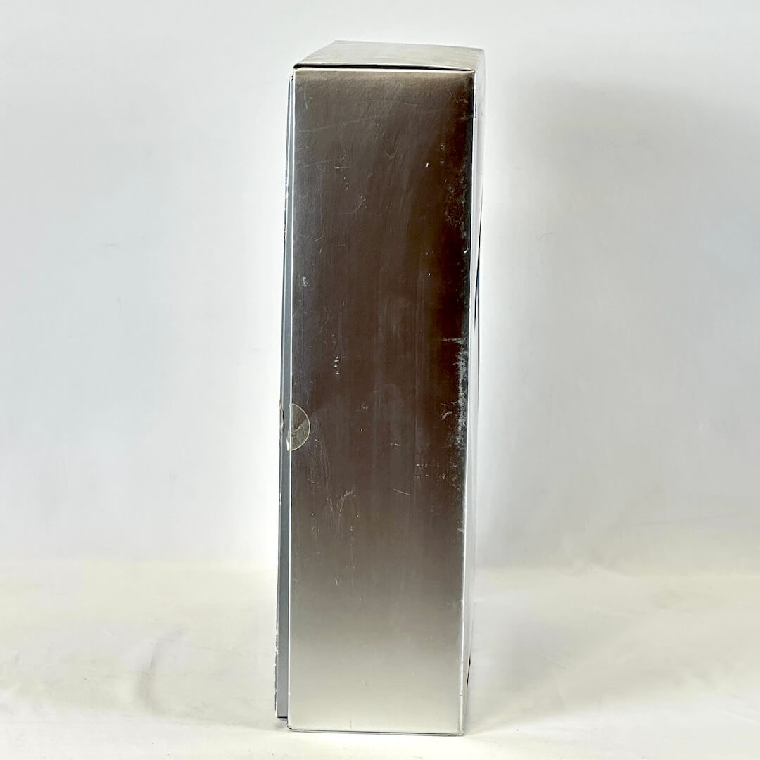 Silver rectangular object on a white background, side view of Barbie packaging.
