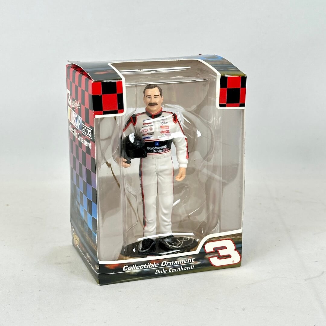 Collectible ornament of a race car driver in packaging with checkered pattern