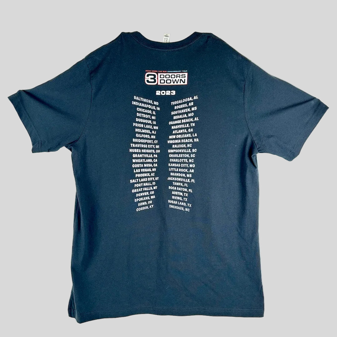 A black t-shirt laid flat, featuring a white graphic print of the 2023 '3 Doors Down' tour city list on the back.