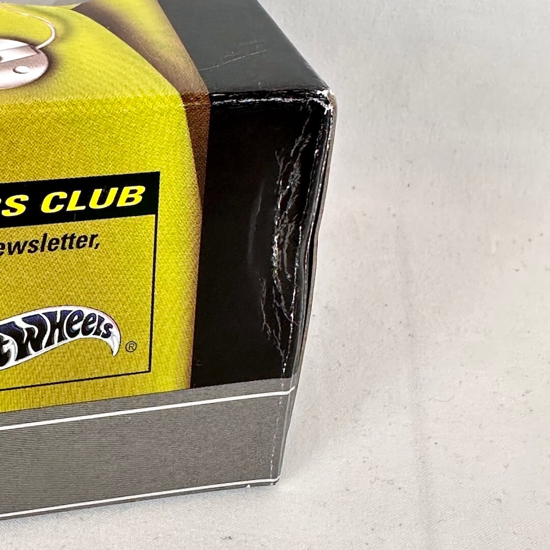 Close-up of a Hot Wheels box corner, showing a bright yellow printed panel with the Hot Wheels logo.