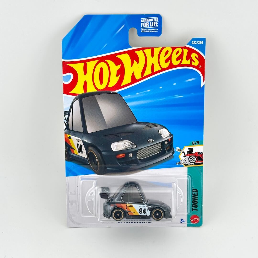 A Hot Wheels Tooned diecast toy car in its original blister card packaging, featuring a black toony race car.