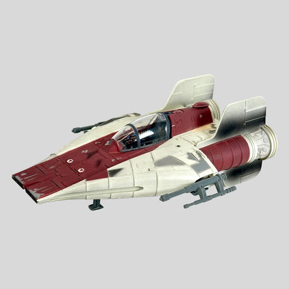 A toy futuristic starfighter spacecraft, featuring a cream and dark red color scheme with gray engine components.