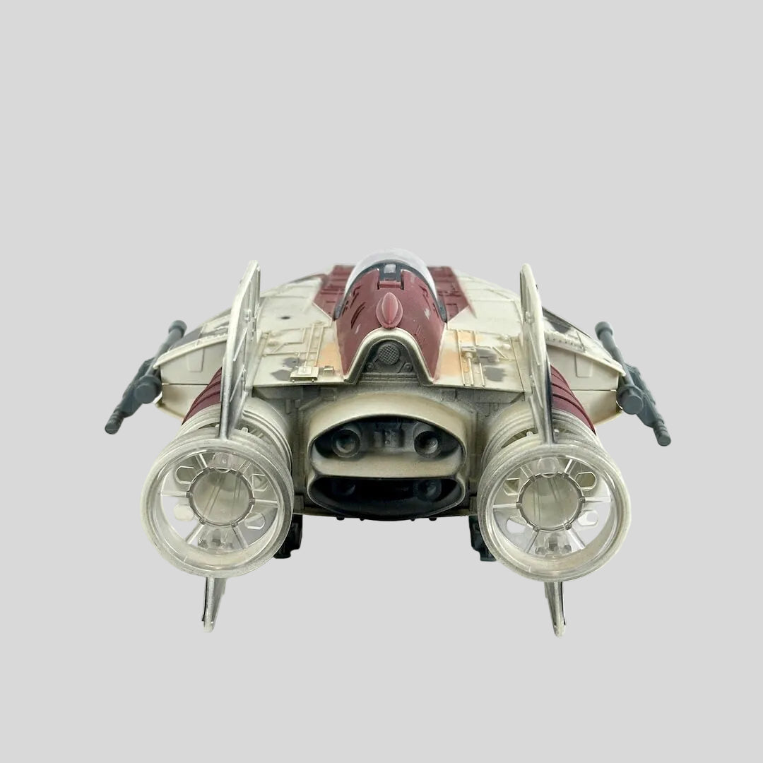 A toy futuristic starfighter spacecraft, featuring a cream and dark red color scheme with gray engine components.