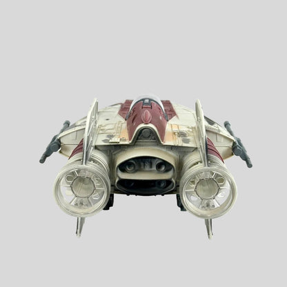 A toy futuristic starfighter spacecraft, featuring a cream and dark red color scheme with gray engine components.