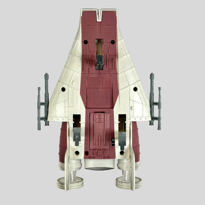 A toy futuristic starfighter spacecraft, featuring a cream and dark red color scheme with gray engine components.