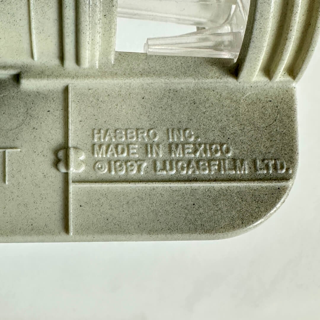 Close-up of a light gray plastic part with embossed text reading 'HASBRO INC. MADE IN MEXICO © 1987 LUCASFILM LTD.