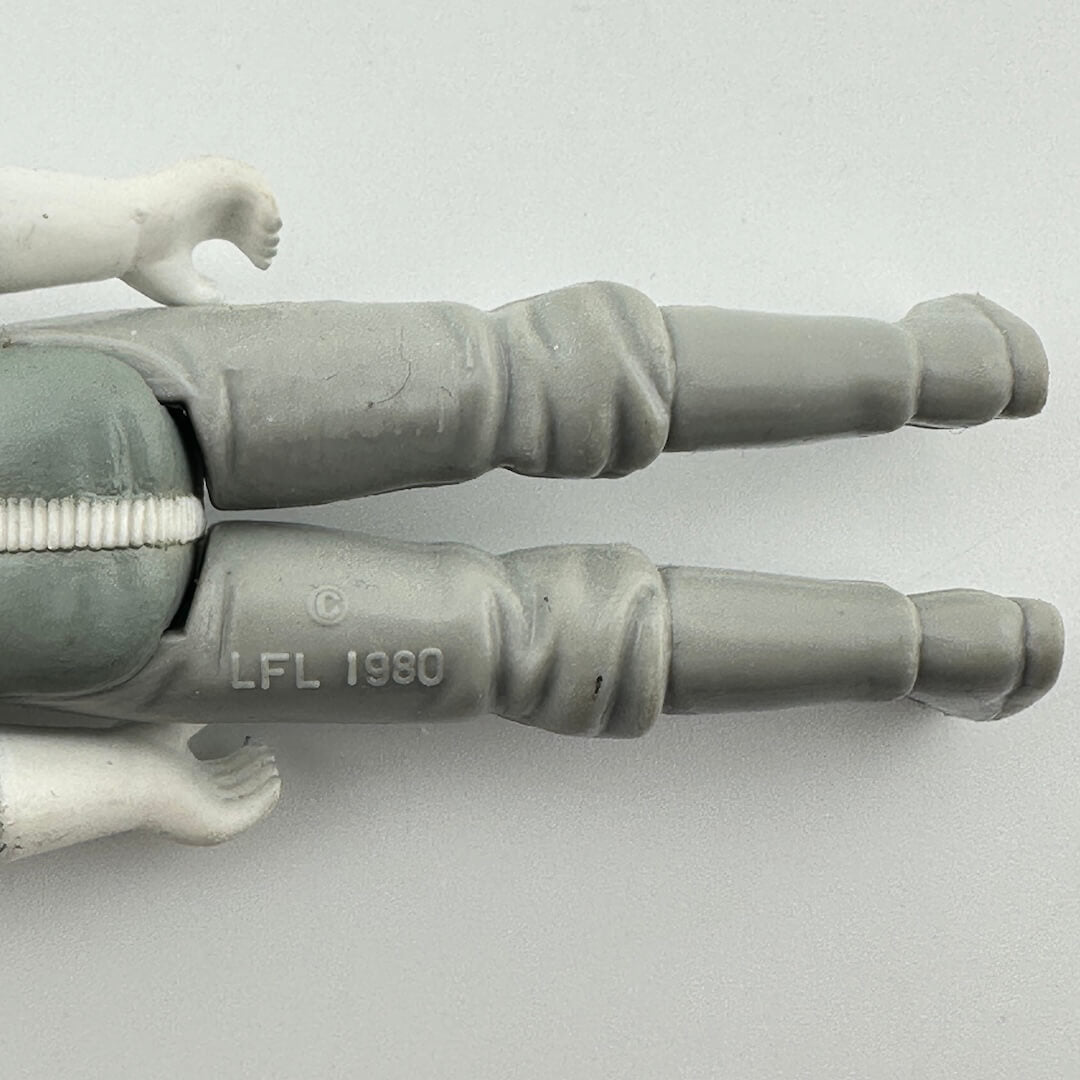 Close-up of a gray action figure's articulated legs and hands, showing the 'LFL 1980' molded into the pants.