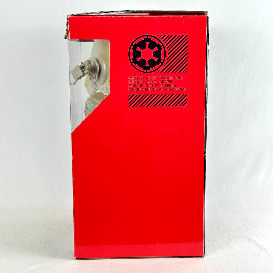 A red Star Wars Imperial crest box with a clear window showing a small figure inside, photographed against a white background.