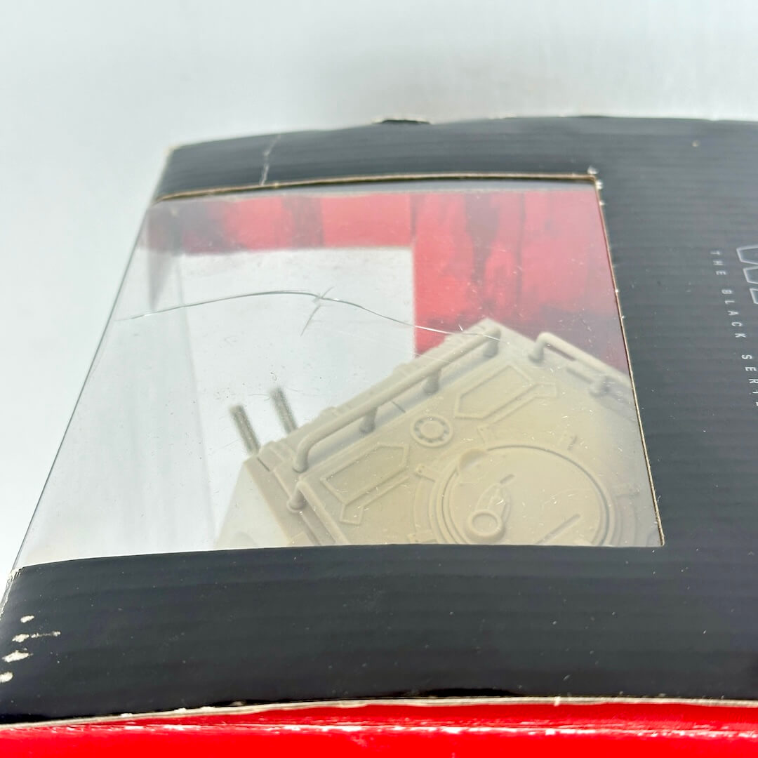 A close-up of a packaged product inside a black box with a clear plastic window.