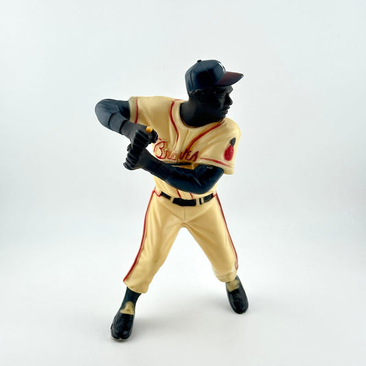 Baseball player in cream uniform with red writing in mid-batting pose with missing bat. 
