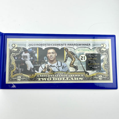 Two-dollar bill with a blue border featuring a sports-themed design and text.