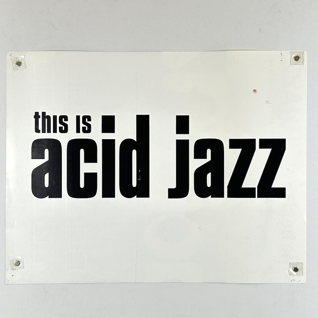 White sign with black text 'this is acid jazz' on a white background